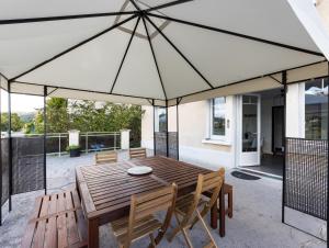 a wooden table and chairs under a large umbrella at - Les Berges du Pont Valentré - in Cahors