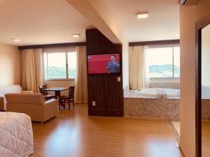 a living room with a tv in a room at Hotel Mirante São Brás in São Brás do Suaçuí