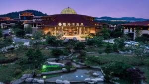 a building with a pond in front of it at Holiday Inn Dalian Hot Spring, an IHG Hotel in Dalian