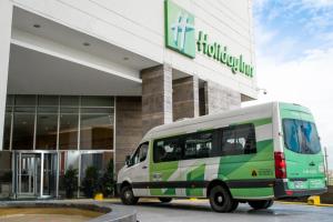 a green and white van parked in front of a building at Holiday Inn Bogota Airport by IHG in Bogotá