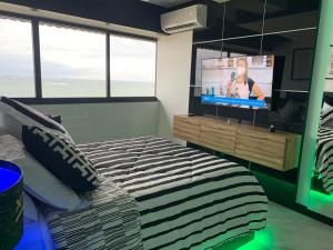 um quarto com uma cama e uma televisão de ecrã plano em Presidential Suite na orla da Praia da Costa em Vila Velha