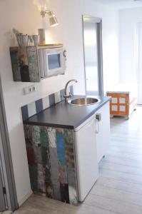 a kitchen with a sink and a microwave at Hotel B&B Altijd Wad in West-Terschelling