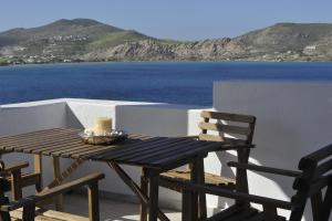 una mesa de madera y sillas en un balcón con vistas al océano en Villa Irini en Naousa