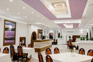 restauracja z białymi stołami i krzesłami oraz fioletowymi sufitami w obiekcie Lawendowy Ogród w Brzegu