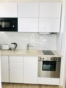 Belvárosi Stúdió Apartman في كيسكيميت: مطبخ بدولاب بيضاء ومغسلة وموقد