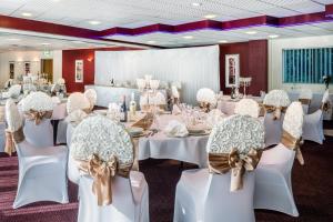 um salão de banquetes com mesas brancas e cadeiras com arcos em Holiday Inn Birmingham North - Cannock, an IHG Hotel em Cannock