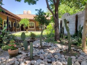 a garden with cacti and rocks in front of a house at Posada Argimon in San Marcos Sierras