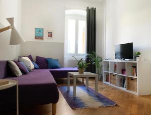 un soggiorno con divano viola e TV di Casa Strehler a Trieste