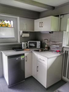 a kitchen with white cabinets and a sink and a microwave at Apartament Bukowy in Szczyrk