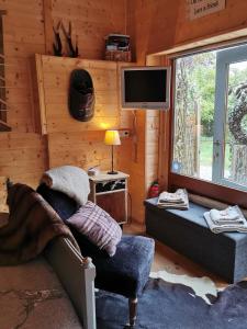 Cabaña con sala de estar con sofá y TV. en Le Cerf d'Hubert, en Redu