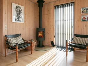 a living room with a stove and two chairs at 6 person holiday home in Fjerritslev in Fjerritslev