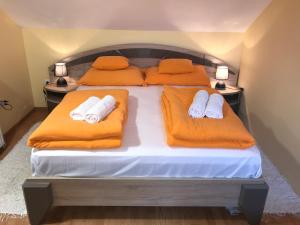 a bedroom with two beds with orange pillows at Tó- Party Panoráma Panzió & Wellness in Kiszombor