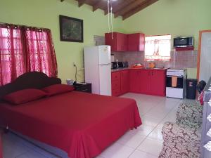 a bedroom with a red bed and a kitchen at Tequila Sunrise Antigua in Osbourn