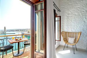 a room with a balcony with a table and chairs at Vista Del Porto Luxury Suites in Rethymno Town