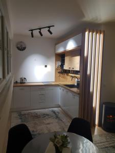 a kitchen with white cabinets and a table with chairs at Apartman ZELENA BAJKA- Bjelašnica in Bjelašnica +18 photos