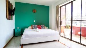 a bedroom with a white bed and a green wall at Casa Colonial Tulum in Tulum