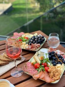 una mesa de madera cubierta con platos de comida y copas de vino en Masarotto Luxury Chalet #2 en Belgrado