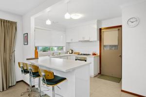 Korumburra的住宿－Cosy Cottage 2BR, NETFLIX, Private Garden Terrace，厨房配有白色的柜台和椅子