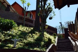 una casa con escaleras y una cruz en el césped en Pousada e Restaurante Tio Paulo, en Teresópolis