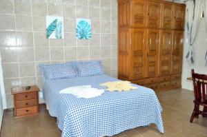 1 dormitorio con 1 cama con manta blanca y azul a cuadros en Pousada e Restaurante Tio Paulo, en Teresópolis