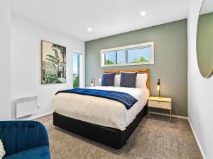 a bedroom with a large bed and a blue chair at Highview Haven by Relaxaway Holiday Homes in Queenstown
