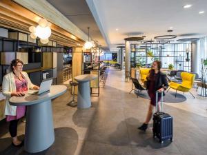 two women with luggage in an office with a table and a laptop at ibis Hotel Muenchen City West in Munich