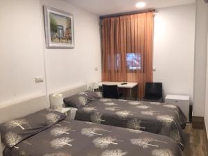 a bedroom with two beds and a desk and a table at Rooms H Skyline in Alcorcón