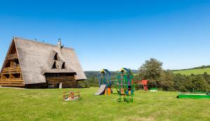 a group of playground equipment in a field next to a thatched building at Wille Trójca in Trójca