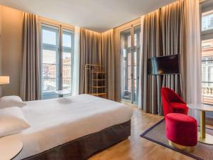 a hotel room with a large bed and red chairs at Ibis Styles Toulouse Capitole in Toulouse