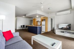 a living room with a couch and a table and a kitchen at The Docks On Goodwin in Brisbane