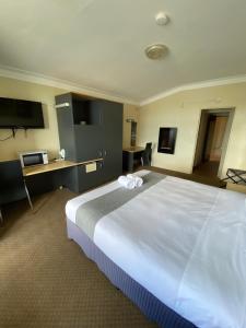 a hotel room with a large white bed in it at Taree Motor Inn in Taree