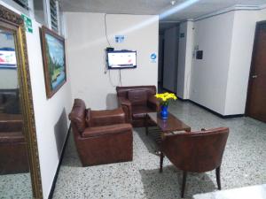 una sala de espera con sillas, mesa y TV en Hotel Central Confort Plaza, en Villavicencio