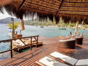 una terrazza in legno con sedie, ombrelloni e acqua di Mar da Lua a Praia de Araçatiba