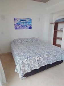 uma cama num quarto branco com um cobertor em Casa do Francês na Praia em Boa Vista