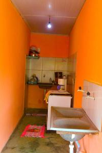 a kitchen with orange walls and a kitchen with a sink at Hospedaria Caribe in Cumuruxatiba