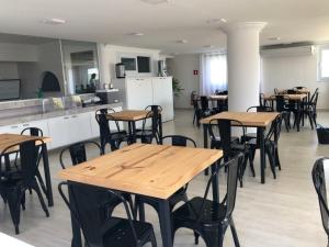 a room with wooden tables and chairs and a kitchen at Arraial D'Ajuda, Altos da pitinga ,3 suítes in Arraial d'Ajuda
