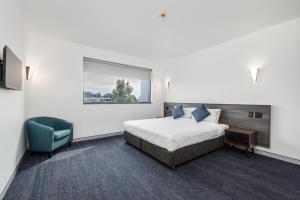 梅特兰Thornton Executive Hotel的一间卧室，有一张床和一把蓝色椅子