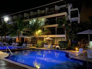 a swimming pool in front of a hotel at night at Nannai - Muro Alto - Alto Padrão in Porto De Galinhas