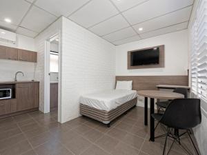 a room with a bed, table and a microwave at Chalet Motor Inn in Bundaberg