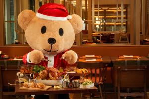 a teddy bear wearing a santa hat standing at a table with food at Shangri-La Yuanqu, Suzhou in Suzhou