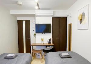 Mały pokój z 2 łóżkami i biurkiem w obiekcie nestay apartment tokyo nippori w Tokio