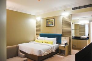 a hotel room with a bed, chair, and nightstand at UCSI Hotel Kuching in Kuching