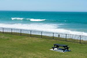 a bench sitting next to a fence near the ocean at Meridian Beachside Apartments in Old Bar