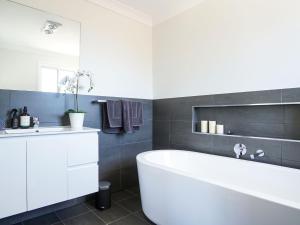 a bathroom with a white tub and a sink at Blissful Bungalow in Culburra Beach