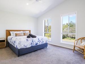 a bedroom with a bed and two windows at Blissful Bungalow in Culburra Beach