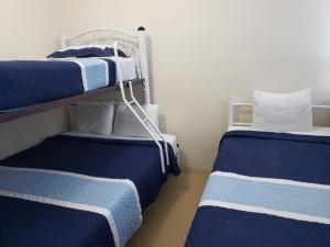 two beds in a room with blue and white stripes at Hostal Ciudad de México - Habitaciones privadas con Wi-Fi en el centro histórico in Mexico City