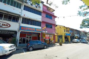 een straat met auto's geparkeerd voor gebouwen bij SPOT ON 90119 Bed's Guesthouse in Kuching