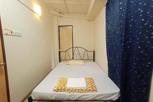 een klein bed in een kleine kamer met een blauw gordijn bij SPOT ON 90119 Bed's Guesthouse in Kuching