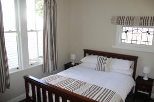 a bedroom with a bed and two windows at Linton Cottage in Palmerston North