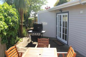a patio with a table and chairs and a grill at Linton Cottage in Palmerston North